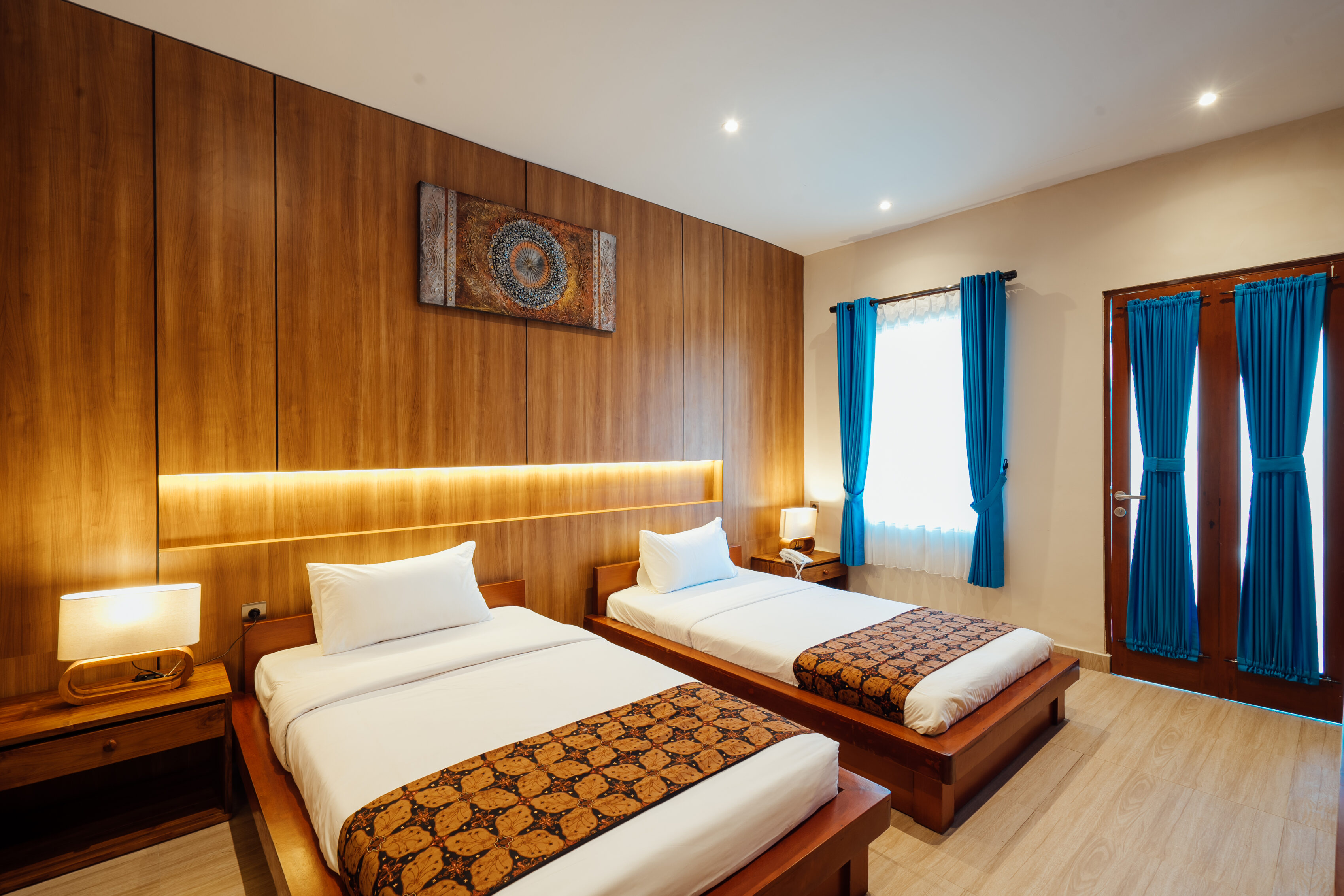 King bed with blue accents and wood-panelled wall in a Bidadari Sanctuary Room