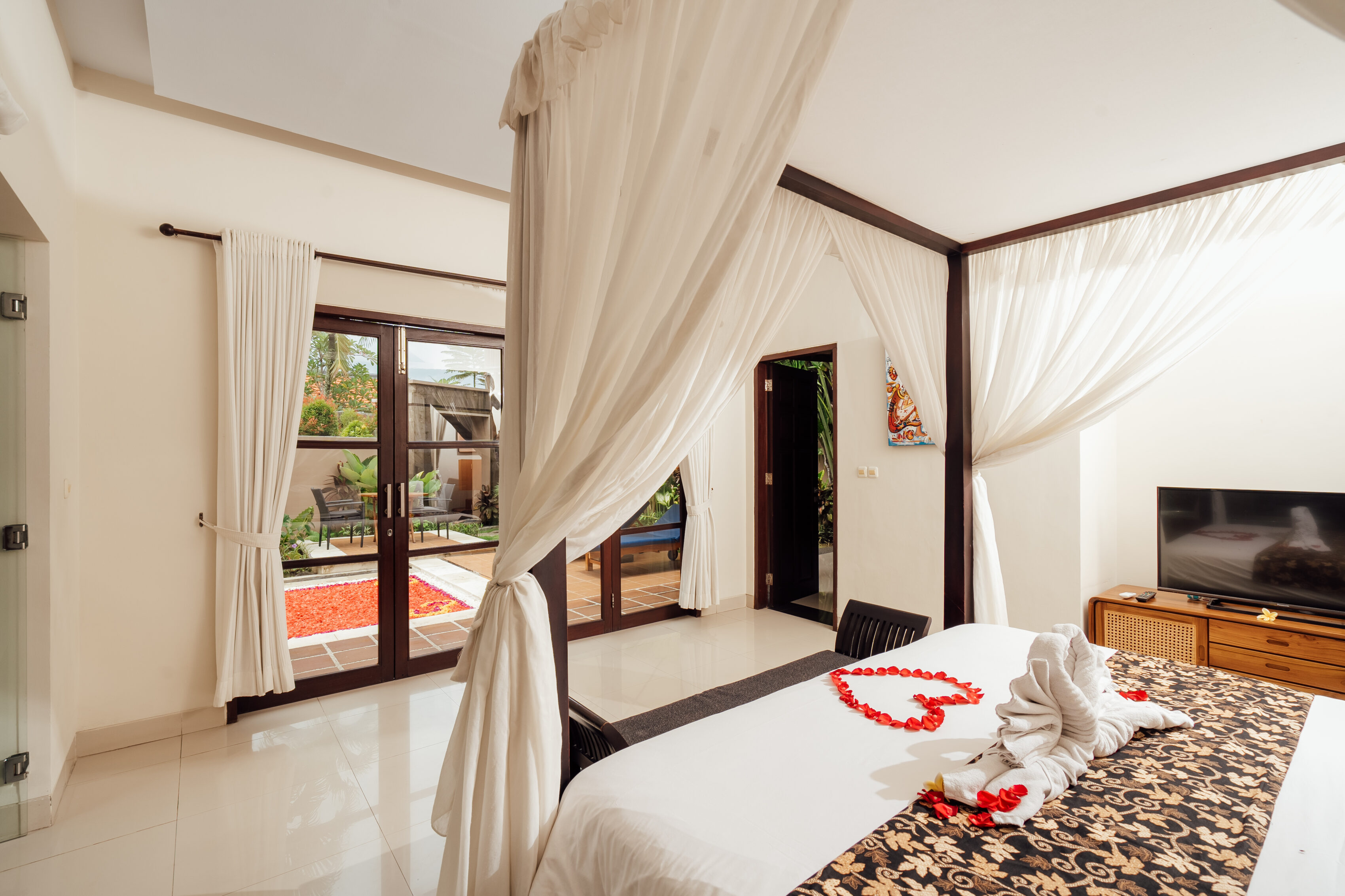 Canopy bed with romantic flower-petal turndown in a villa bedroom, The Bidadari