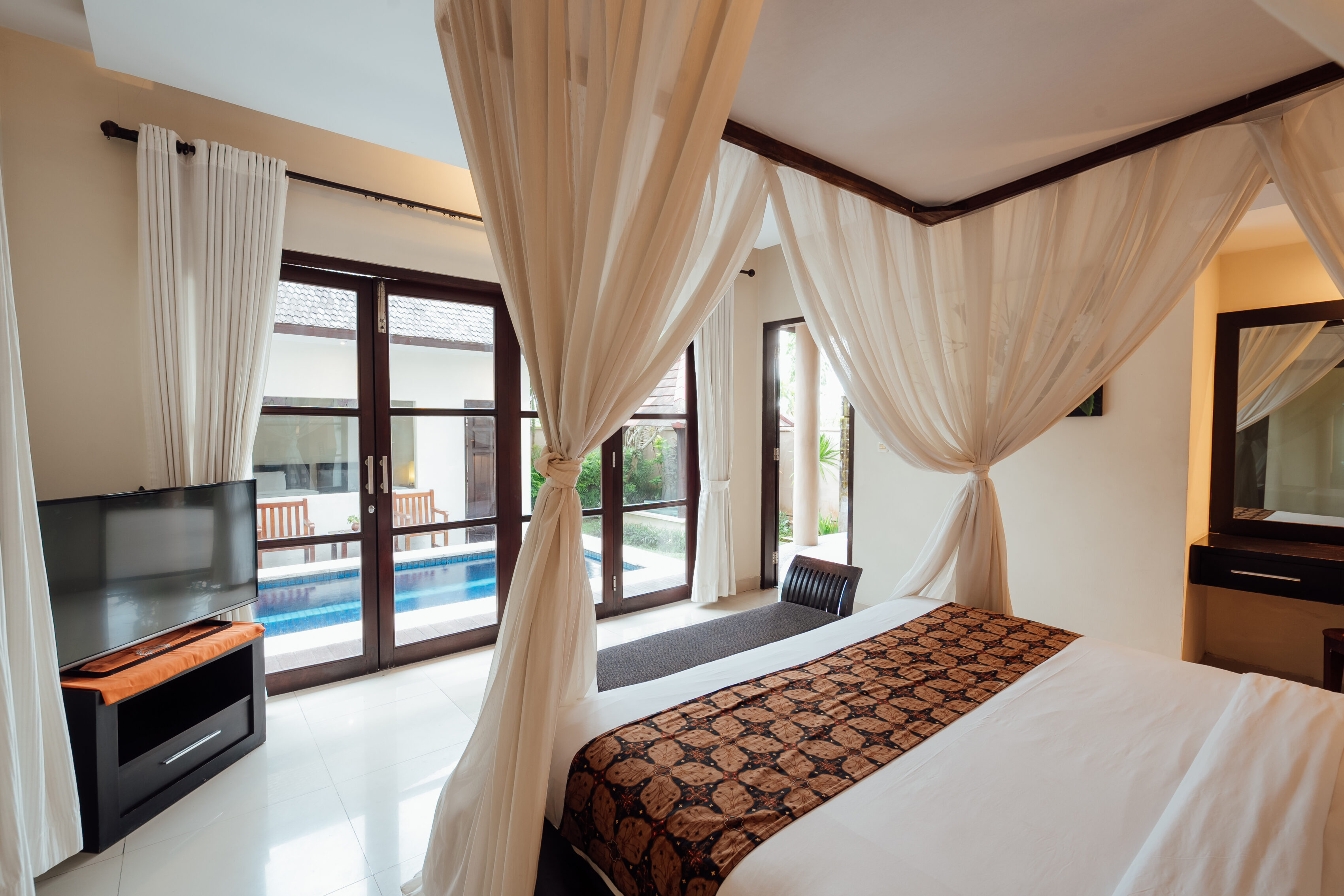 Four-poster canopy bed opening to the pool terrace, The Bidadari villa
