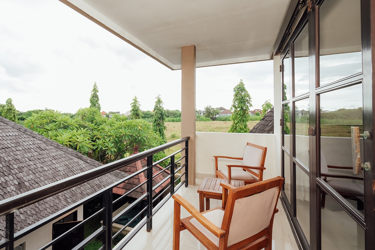 Upper-floor villa terrace with wooden table overlooking rice fields, The Bidadari, Bali