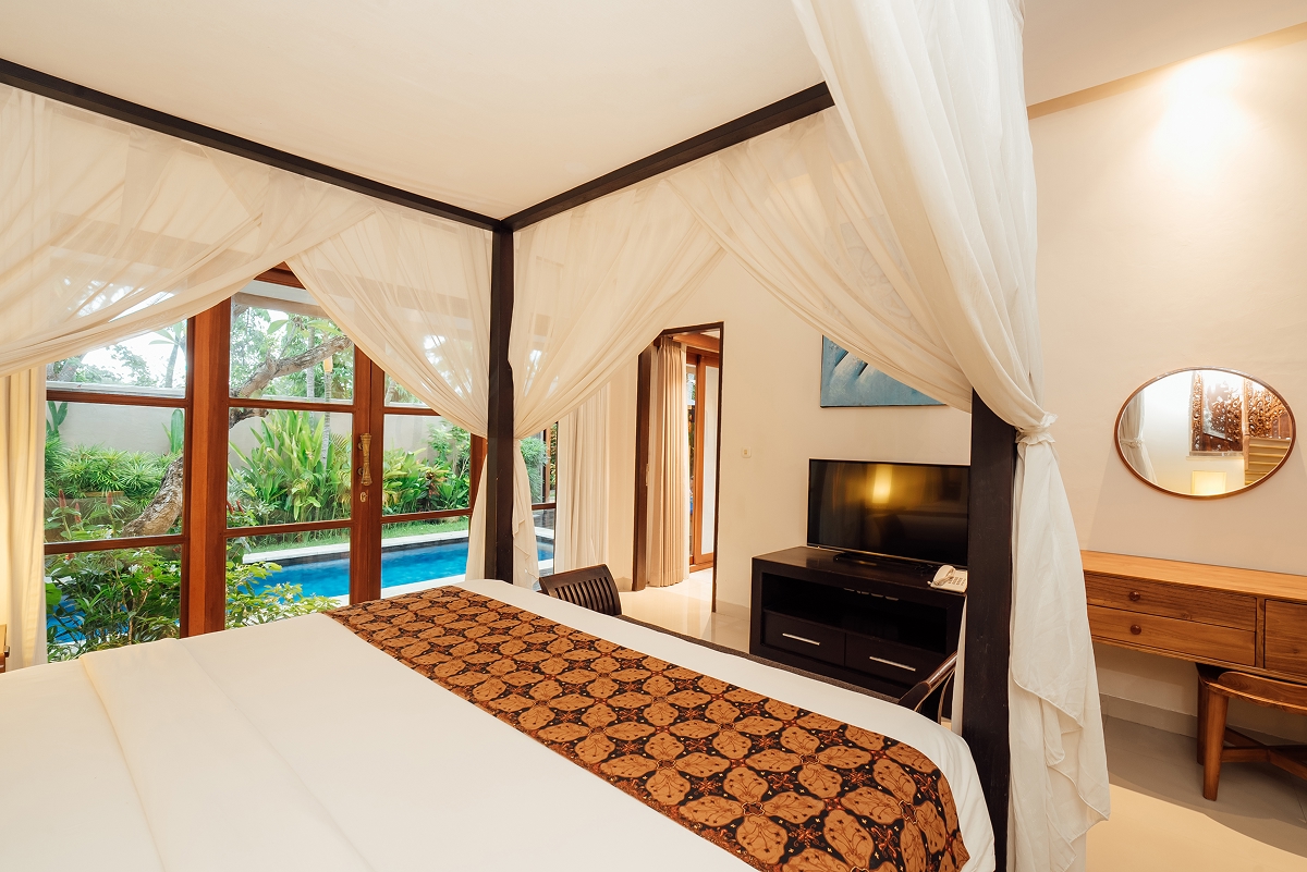 Canopy bed with batik runner and round mirror in a villa bedroom, The Bidadari