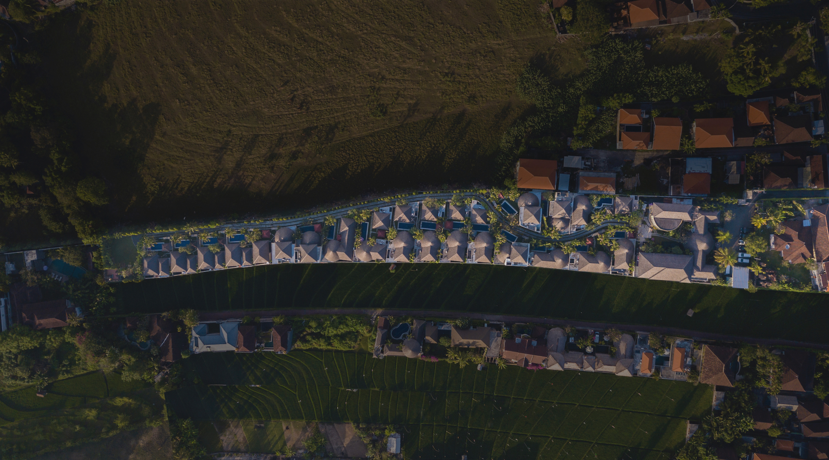 Aerial view of The Bidadari Villas & Spa at dusk, thatched-roof villas amid tropical gardens, Umalas, Bali
