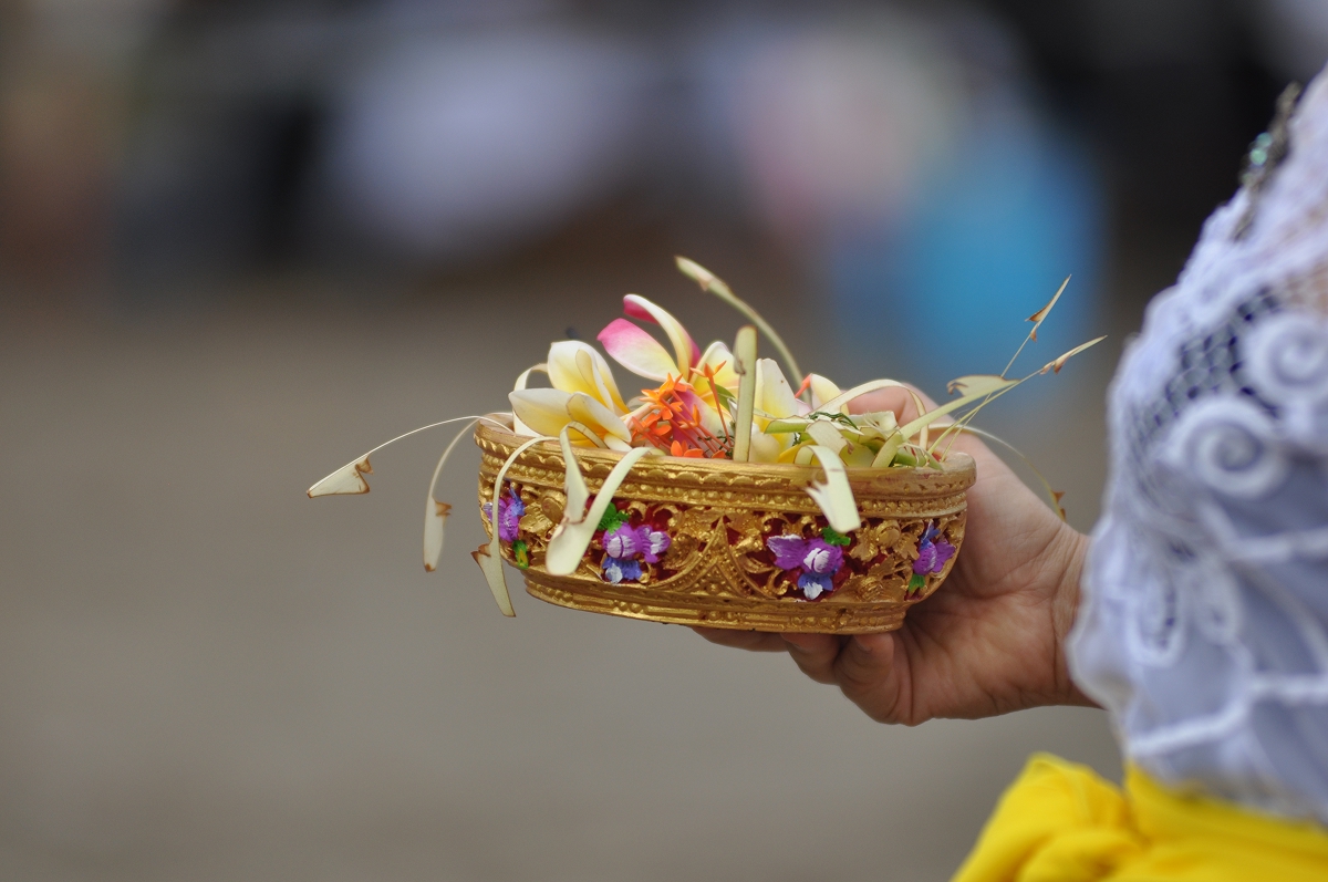 Close-up of hands holding a Balinese canang sari flower offering