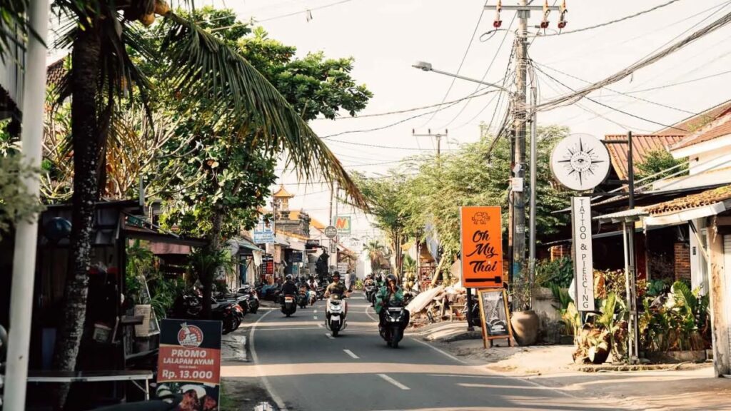 Busy street with scooters and shops in Canggu Bali