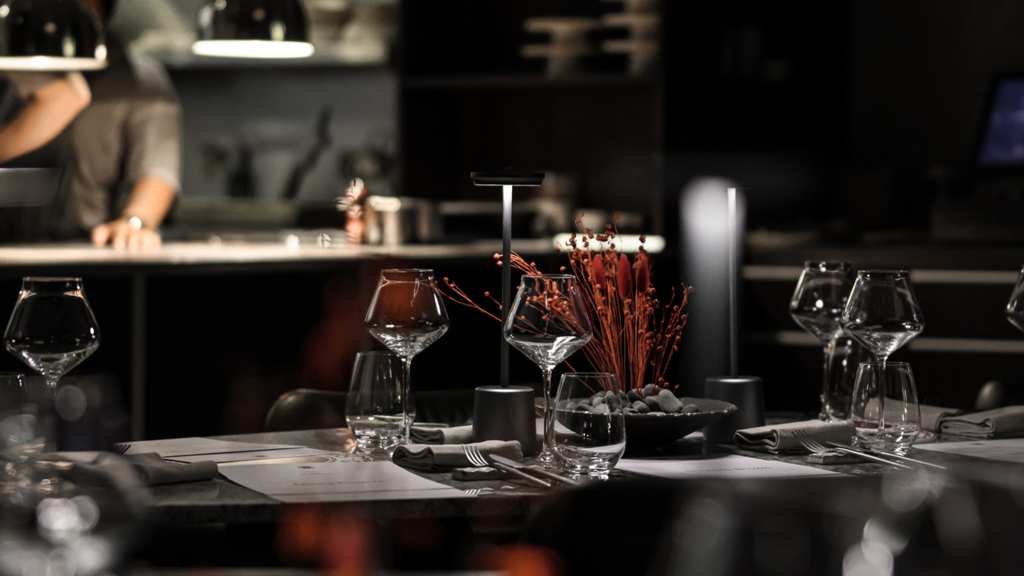 Elegant fine dining table setting with wine glasses and minimalist decor in a dark modern restaurant.