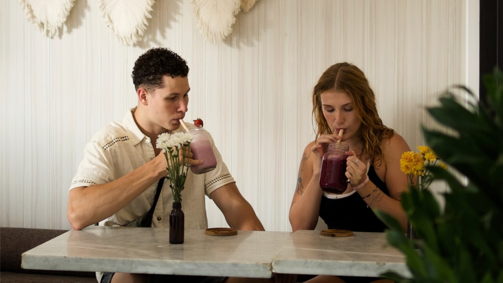 Young couple enjoying colorful drinks together at a bright tropical cafe.
